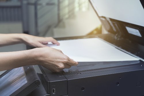 Frau legt ein Blatt Papier auf einen Scanner